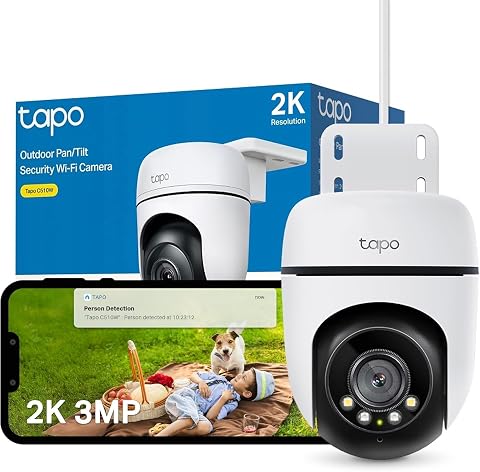 Caméra extérieure PTZ Tapo blanche fixée sur une façade claire dans un décor de jardin discret